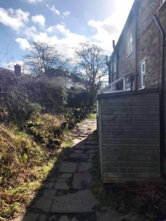 Footpath emerges from behind a house in Rainow