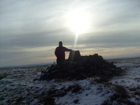 Tom at the summit, under a shaft of sunlight