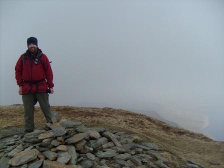 Tom on summit, with a hint of a view of the lake below