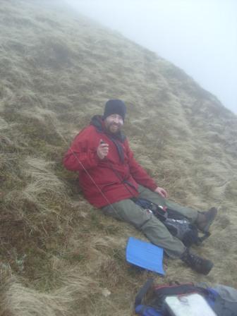 Tom on 2m FM - we were sitting on this steep grassy slope to shelter from the wind