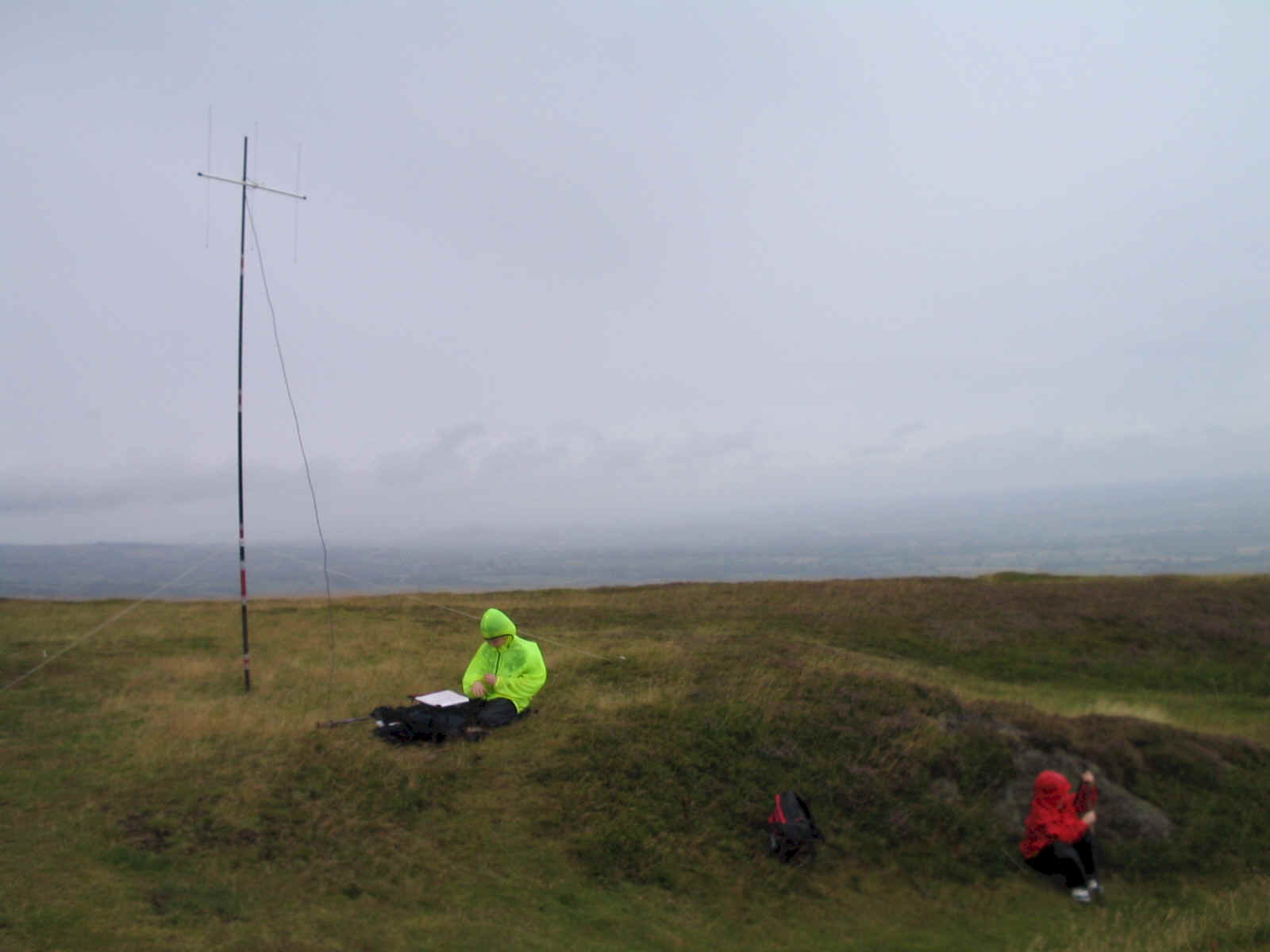 Summit of Caer Caradoc WB-006; Jimmy looks after the radio equipment, while Liam takes shelter!